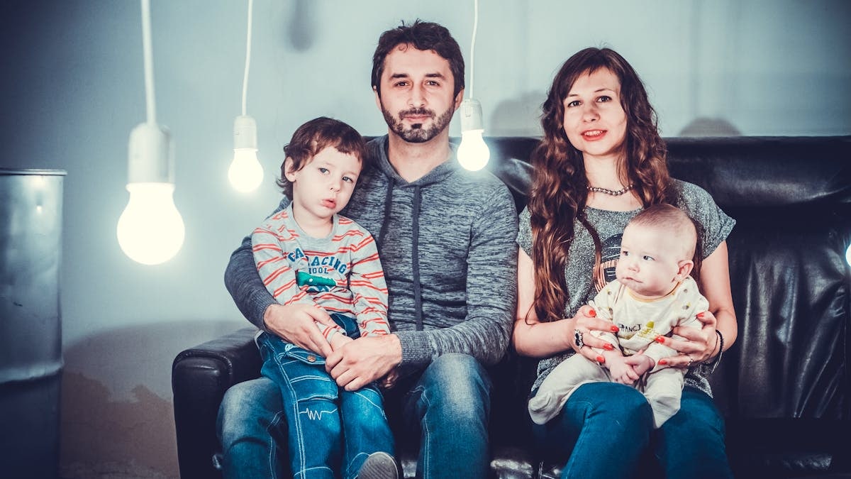 A loving family portrait with parents and children sitting together in a modern, well-lit room.